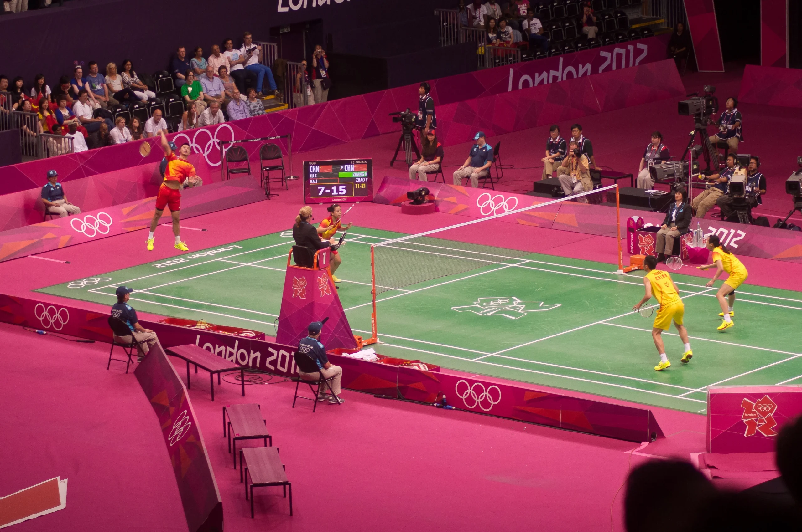 Badminton doubles players positioned on court during a competitive match